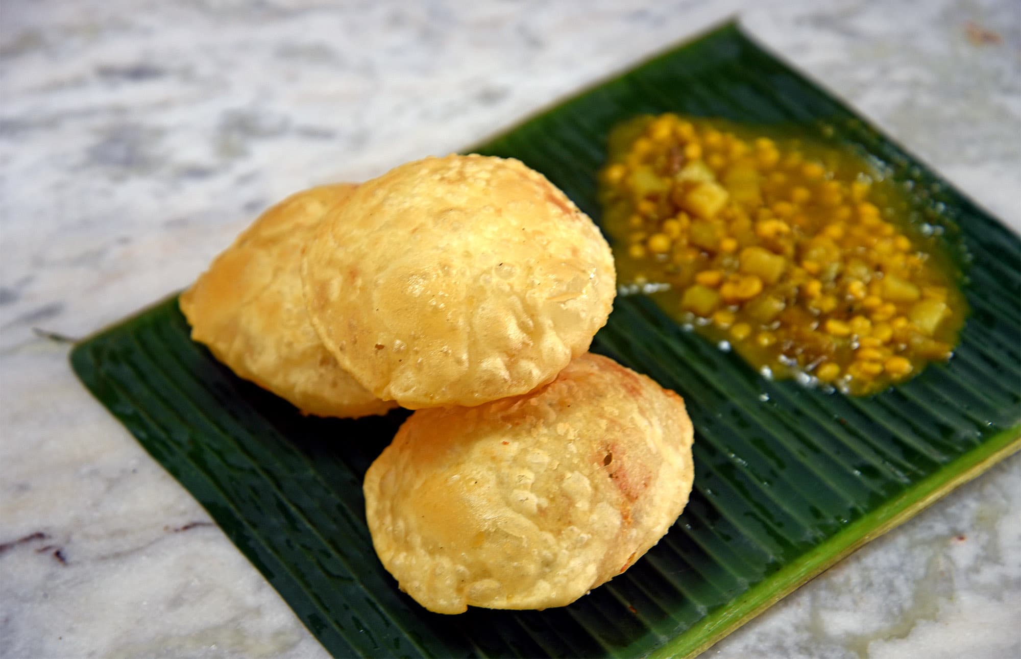 Hot, flaky kochuri served with sweet-savoury chholar dal.