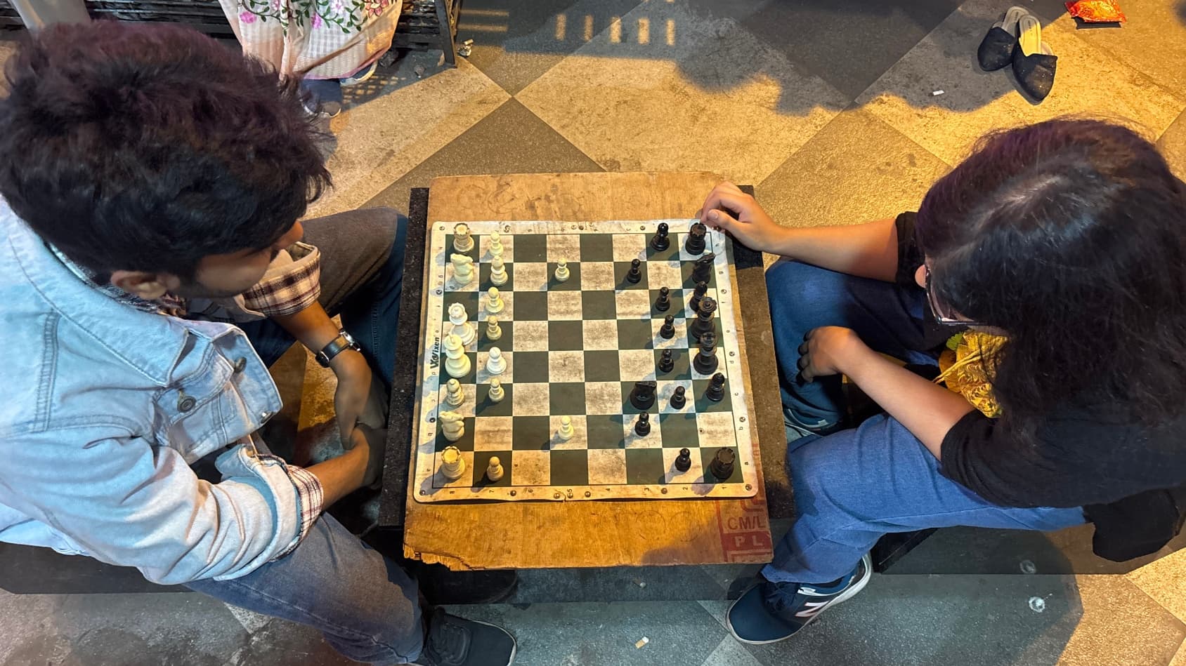 <p>Two players engage in a focused game of chess under the Gariahat flyover.</p>