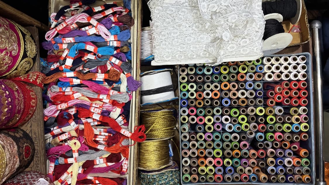 <p>Neatly stacked skeins of embroidery thread are displayed next to rows of colourful spools.</p>
