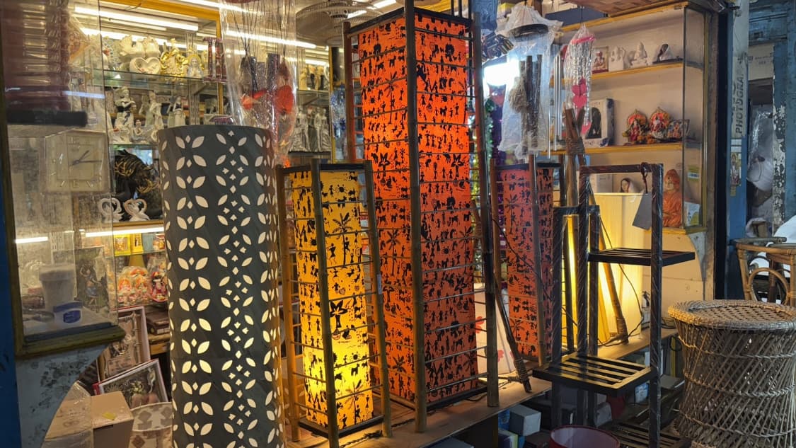 <p>A warm display of handcrafted lamps made from bamboo and fabric, featuring traditional tribal-style (Warli) silhouettes and intricate cut-out patterns.</p>