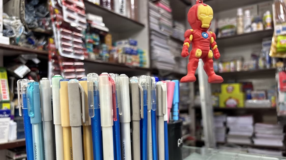<p>Rows of pens line the counter while a small superhero dangles above.</p>